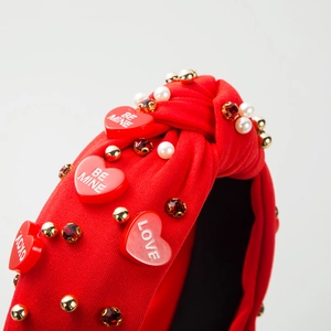 Gros plan du serre-tête noué rouge avec perles, strass et pendentifs cœur Be Mine