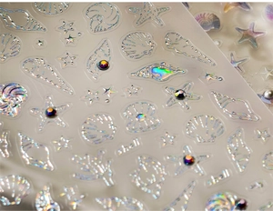 Macro shot of iridescent laser nail art stickers featuring shell and starfish designs