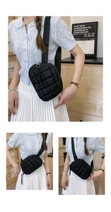 Detail of black quilted puffer bag with fabric strap and round metal zipper ring