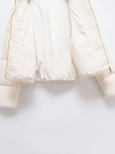 Detailed view of the smooth white lining and gold zipper on a knitted cotton jacket