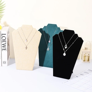 Three velvet and linen necklace display stands showing layered jewelry on counter
