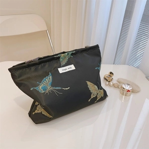 Close-up of butterfly embroidery and texture on a black fabric cosmetic storage bag