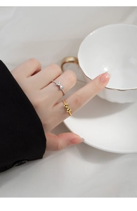 Close-up of stylish sterling silver bow rings in gold and silver finish on a model hand
