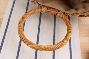 Detailed close-up of a handmade straw bucket bag with round rattan handle and fabric lining