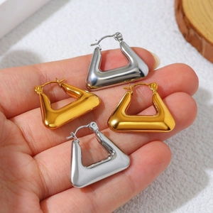 Polished 18K gold and silver geometric triangle earrings held by hand on a white background