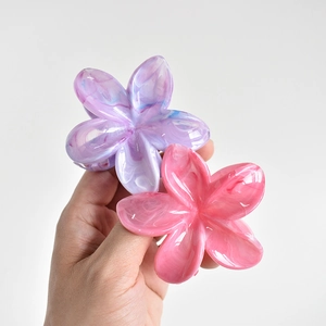 Detail of pink and purple marble texture frangipani hair claw clips held in hand