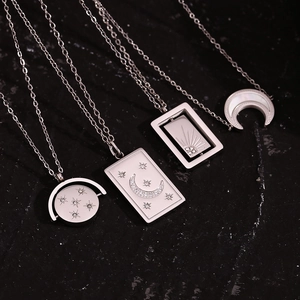 Detailed view of silver celestial necklaces with star and moon charms on dark textured background