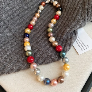 Flat lay of colorful pearl necklace on a grey sweater with elegant lighting detail