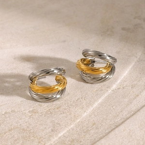Detailed view of two-tone gold and silver C-shaped earrings on textured stone background