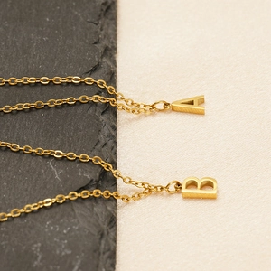 Macro detail of golden letter A and B pendants on a stainless steel necklace chain