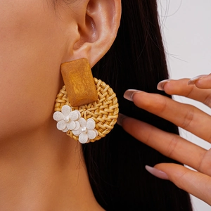 Close-up of Bohemian rattan woven earring with white fabric flower on a female model