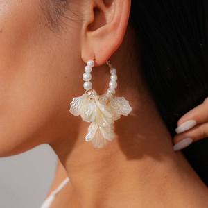 Detailed side view of large gold hoop earrings with pearls and translucent white petals