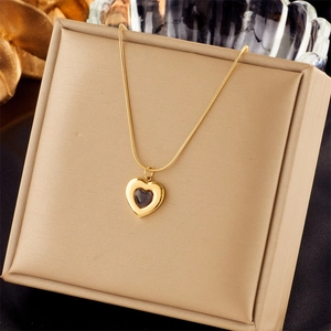 Close-up of golden necklace with heart pendant in a light gold jewelry gift box