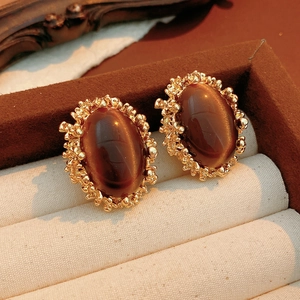 Macro view of vintage oval tiger eye earrings in a textured gold frame within a jewelry box