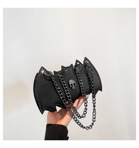 Close-up of black bat-shaped crossbody bag featuring a silver metal skull ornament