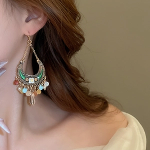 Close-up of Bohemian crescent earrings with multicolored beads and crystals on a model