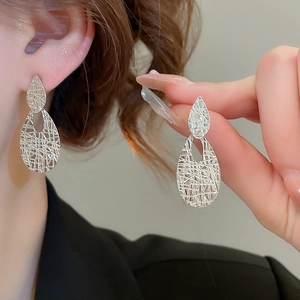 Macro shot of silver teardrop earrings with textured surface and hollow design