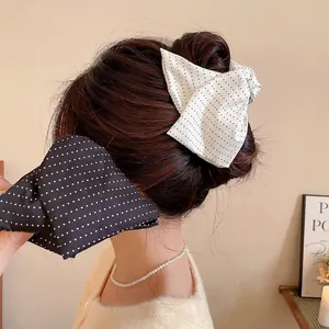 Elegant polka dot bow hair clip for women featuring classic black and white fabric designs