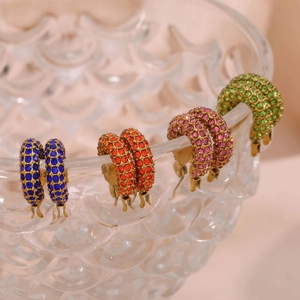 Detailed close-up of colorful crystal paved gold hoops on a decorative glass rim