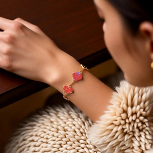 Détail du bracelet plaqué or 18k avec breloques en cœur à rayures rouges et violettes au poignet