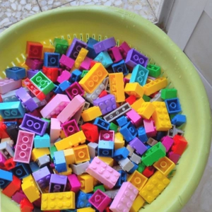 Assorted colorful building blocks for kids in a green container for DIY creative play