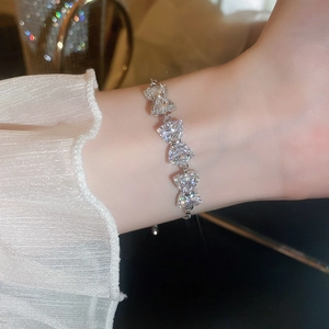 Detailed close-up of a silver bracelet featuring five heart-shaped zircon stones on a wrist