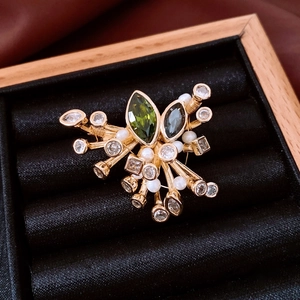Detail of vintage French court style gold brooch with green crystals and pearls in box