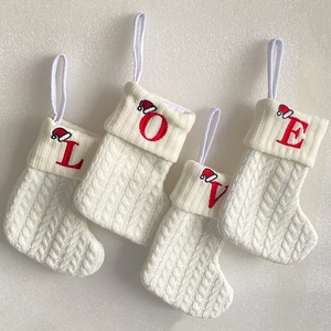 Macro view of four white knitted Christmas stockings with red embroidered LOVE letters
