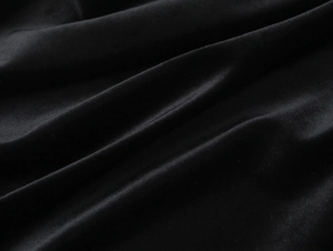 Macro del tessuto in velluto nero con lucentezza morbida e dettagli di drappeggio eleganti