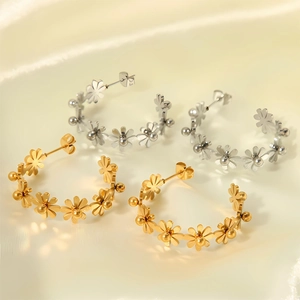 Détails de boucles d'oreilles fleurs en forme de C, finitions dorée et argentée sur tissu