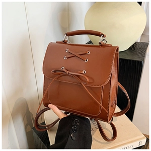 Detailed view of caramel brown faux leather backpack with bow accent and top handle strap