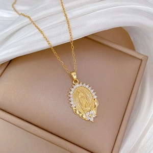 Detailed shot of gold plated Virgin Mary pendant with crystals on silk fabric