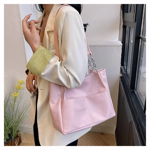 Borsa tote rosa in pelle PU con tracolla a catena e tasca frontale indossata