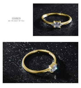 Macro detail of gold square zircon ring with minimalist side stones on dark background