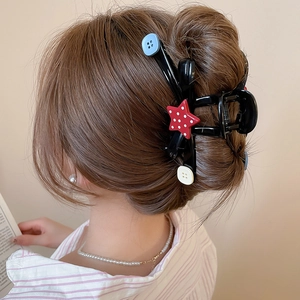 Back view of a large acrylic shark clip with star and button patterns on long hair