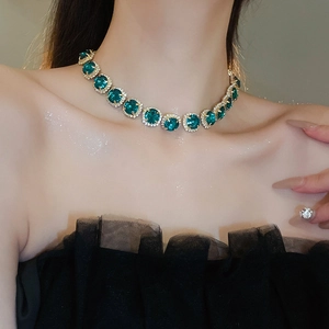 Close-up of model wearing luxury emerald green stone necklace with sparkling gold setting