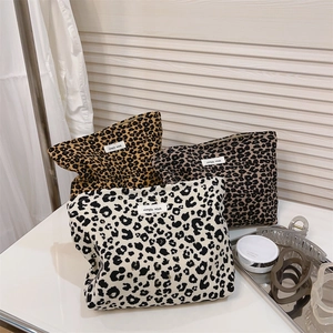 Detailed view of leopard print canvas makeup bags in yellow, brown, and off-white colors