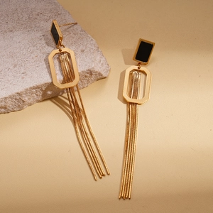 Détail de boucles d'oreilles dorées à pampilles avec incrustation noire sur pierre