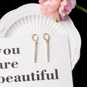 Close-up of golden tassel earrings with sparkling crystals on a decorative white plate