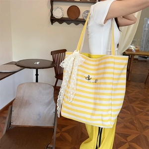 Close-up of yellow striped canvas tote with butterfly embroidery and lace bow details