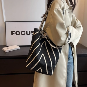 Detail of knit shoulder bag featuring black and white wavy patterns and woven texture