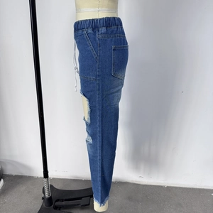 Detail of blue ripped jeans showing elastic waistband, white drawstrings, and denim texture