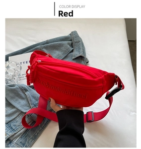 Detail view of red canvas chest bag with embossed letters and adjustable strap