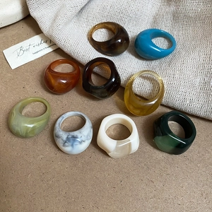 Close-up of colorful geometric resin rings in marble and amber finishes on linen cloth