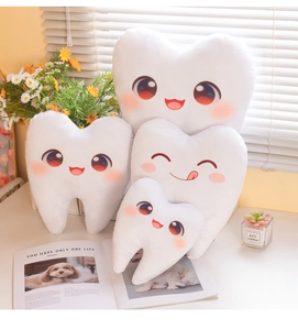 Détail de quatre coussins en peluche en forme de dents de différentes tailles sur une table