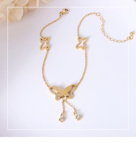 Macro shot of gold butterfly charms and zircon droplets on a minimalist titanium steel chain