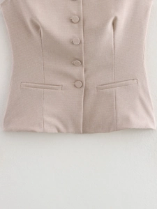 Dettaglio del gilet a quadri beige con trama del tessuto, bottoni e tasche finte