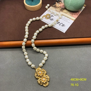 Detail of vintage necklace featuring round pearls and large gold double flower pendant