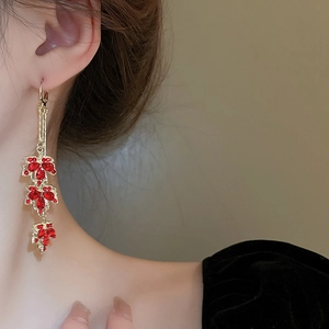 Boucles d'oreilles feuilles d'érable dorées avec strass rouges portées par un mannequin