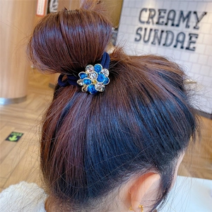 Blue crystal flower hair tie on woman's bun hairstyle in a stylish cafe setting